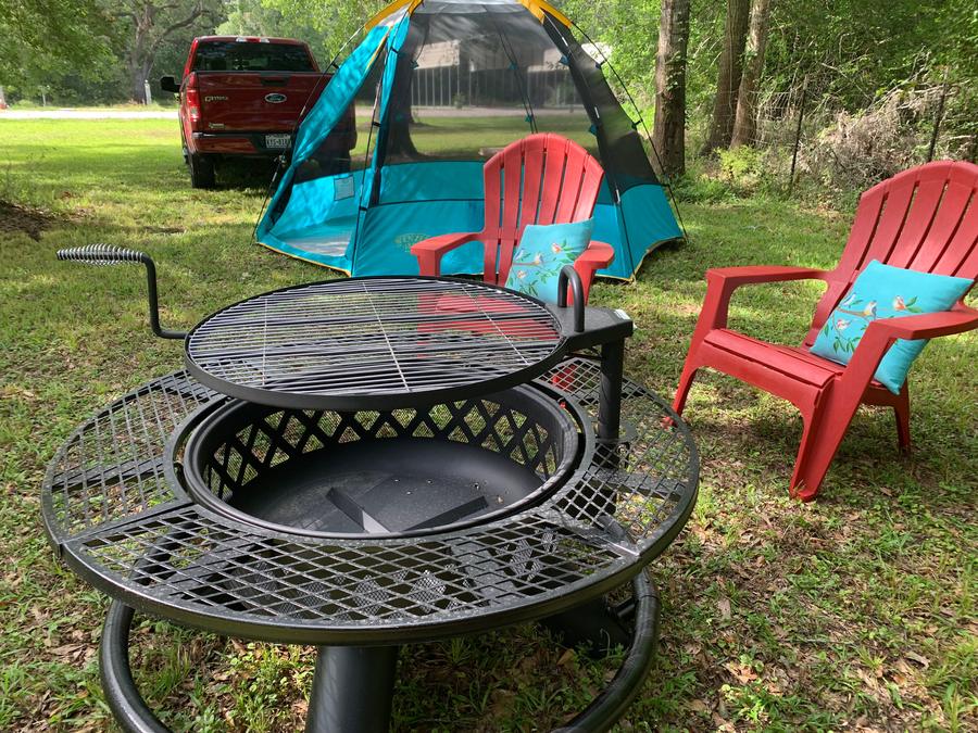 Fire pit with red chairs beside a tent